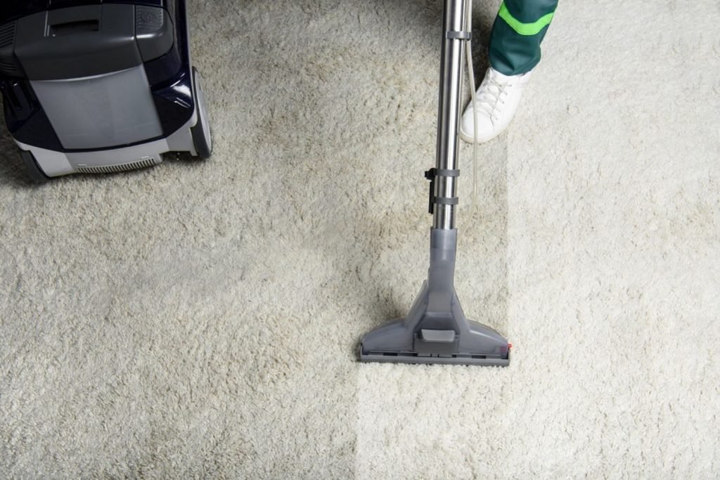 A man cleans a carpet with a vacuum, highlighting a carpet and rug cleaning service based in Houston, TX.
