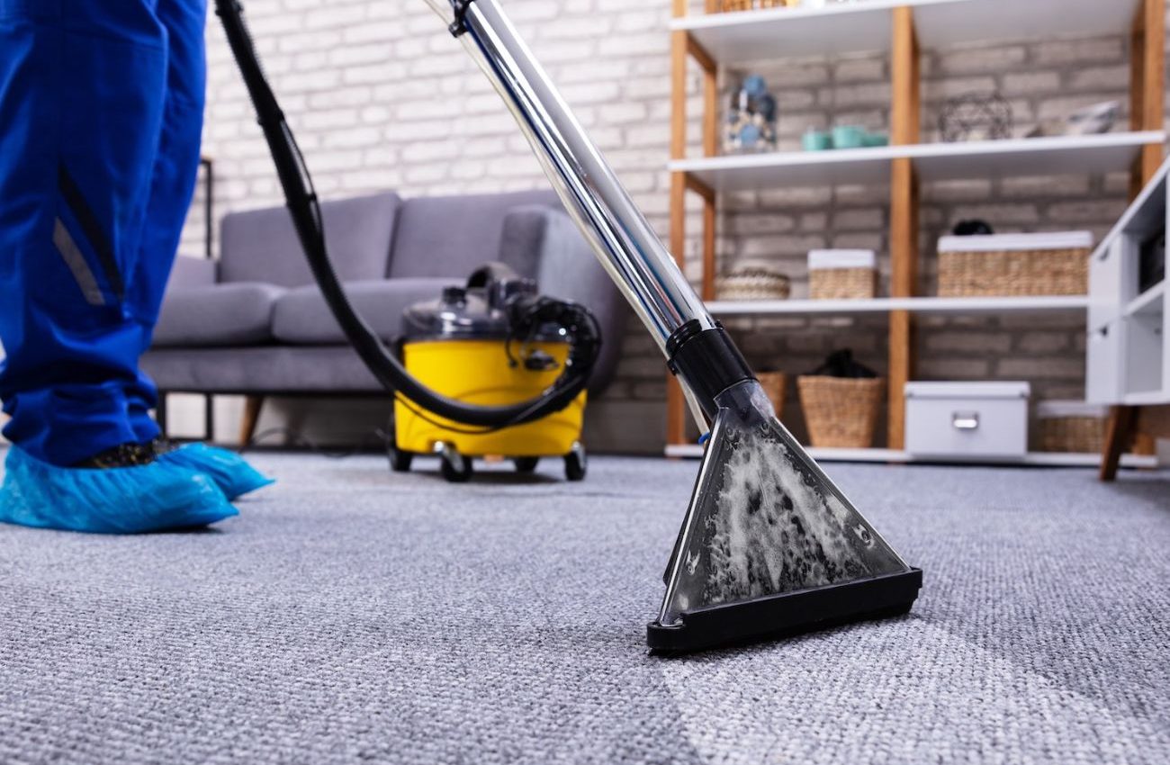 A person operates a vacuum cleaner on a carpet, highlighting a restoration service based in Houston, TX.