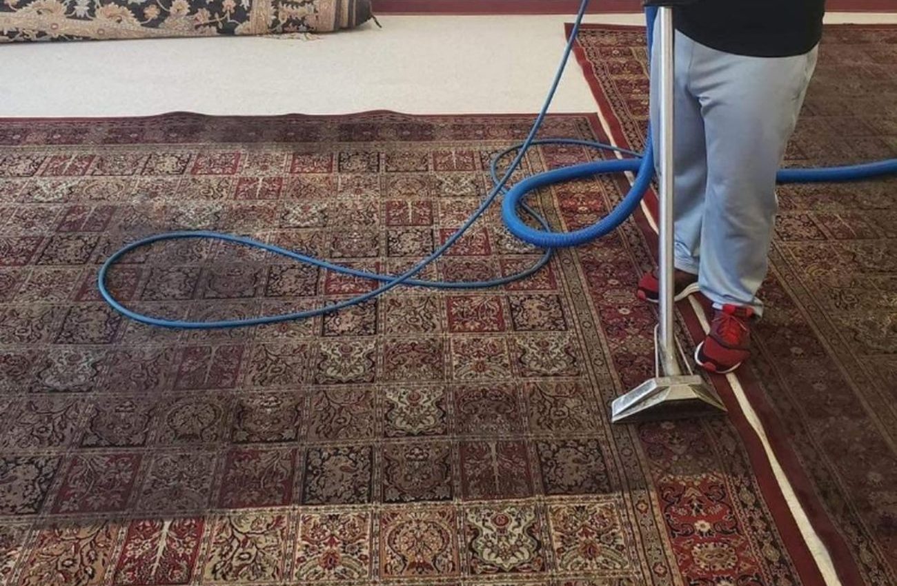 A man cleans an area rug with a vacuum, representing a rug cleaning service in Houston, TX.
